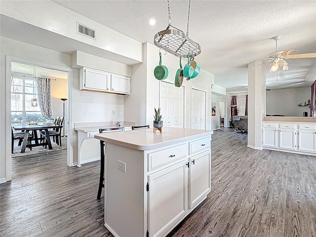 kitchen with ceiling fan, dark wood finished floors, white cabinets, visible vents, and light countertops