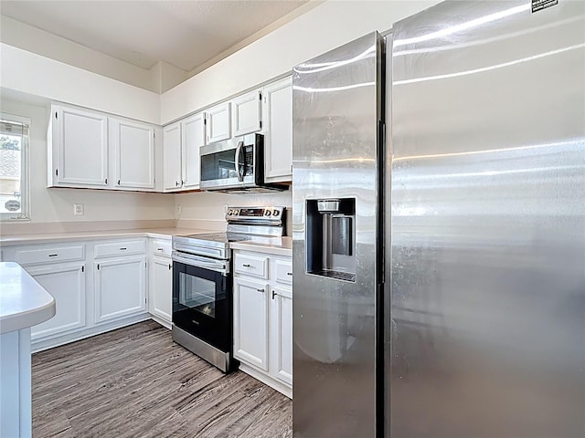 kitchen featuring wood finished floors, white cabinetry, and stainless steel appliances