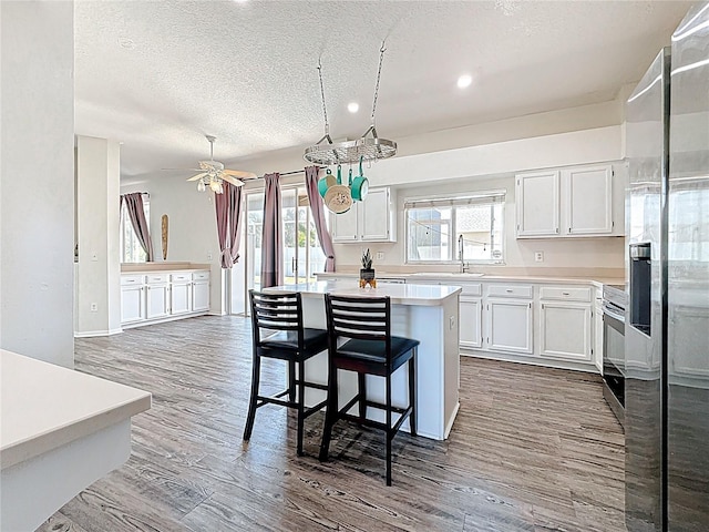 kitchen with a center island, stainless steel fridge, light countertops, a textured ceiling, and dark wood-style floors