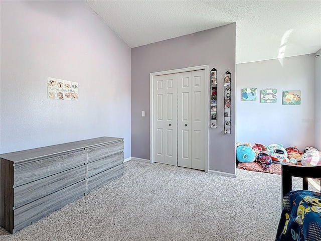 carpeted bedroom featuring a textured ceiling, a closet, and baseboards