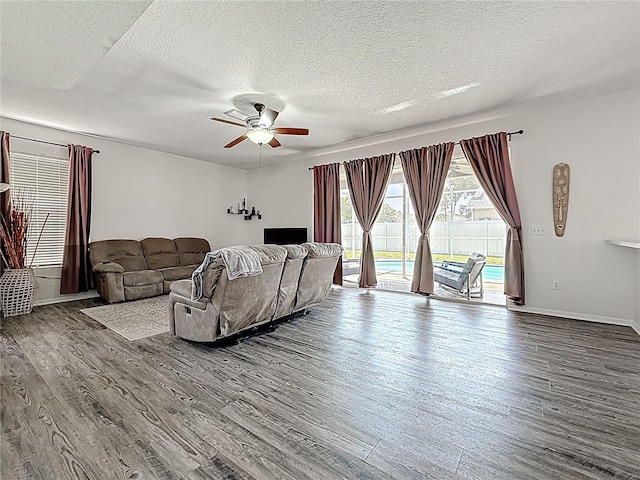 living area with baseboards, a ceiling fan, wood finished floors, and a textured ceiling