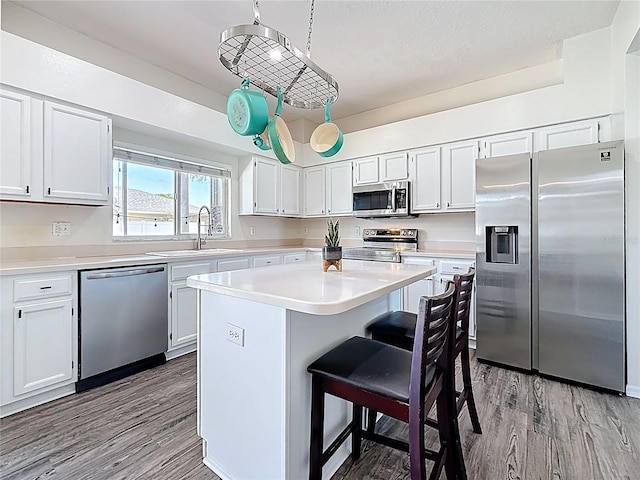 kitchen featuring a sink, a center island, appliances with stainless steel finishes, and wood finished floors