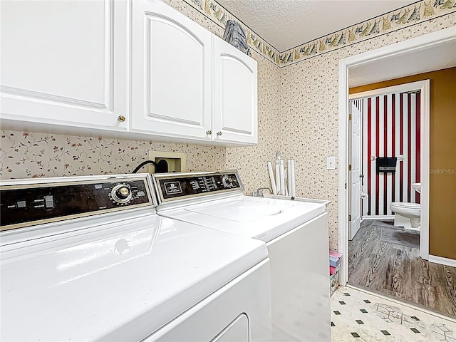 laundry room featuring cabinet space, separate washer and dryer, and a textured ceiling