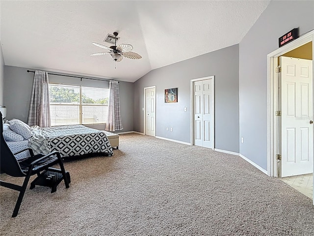 bedroom with light carpet, multiple closets, a textured ceiling, and vaulted ceiling