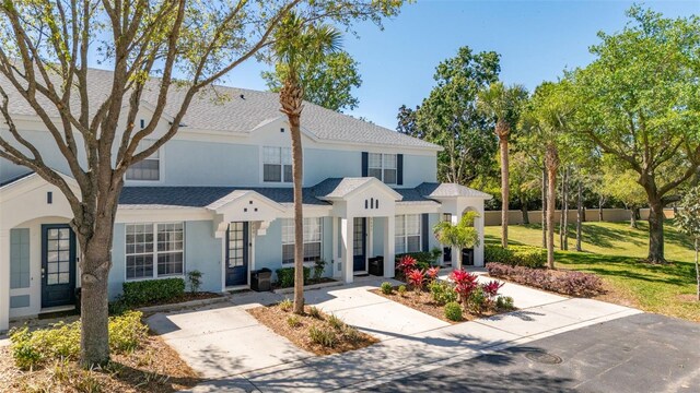 view of property with a front yard, a shingled roof, stucco siding, and fence