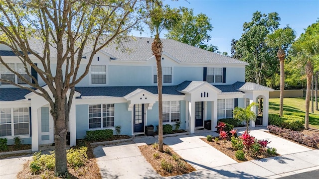 multi unit property featuring stucco siding, fence, and roof with shingles