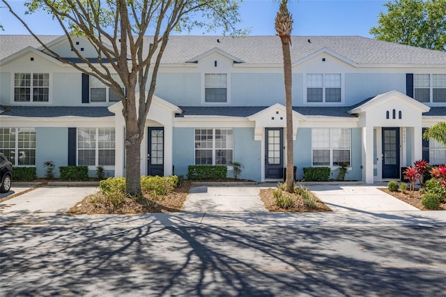multi unit property with stucco siding and a shingled roof