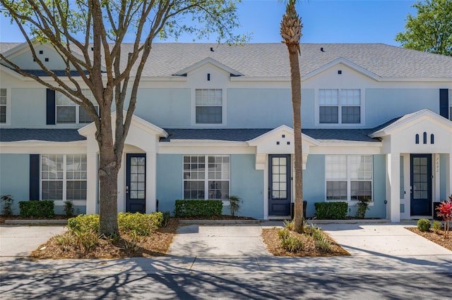 view of property featuring stucco siding and roof with shingles