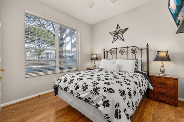 bedroom with a ceiling fan, wood finished floors, and baseboards