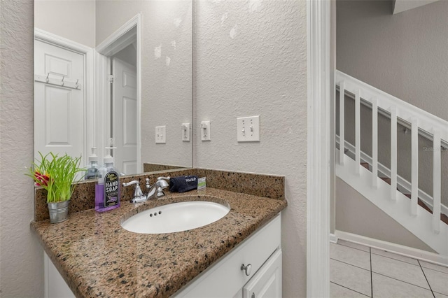 bathroom featuring tile patterned flooring, a textured wall, and vanity
