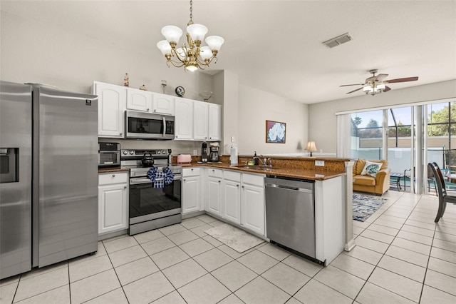 kitchen featuring white cabinetry, appliances with stainless steel finishes, dark countertops, light tile patterned flooring, and a peninsula