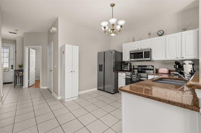 kitchen with light tile patterned floors, dark stone counters, white cabinets, a sink, and stainless steel appliances
