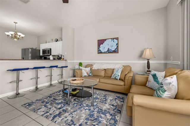 living room featuring light tile patterned floors, a chandelier, and baseboards