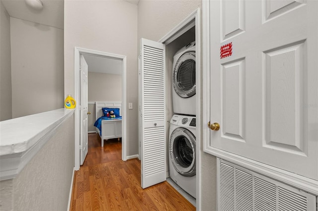 washroom with stacked washer / dryer, visible vents, laundry area, and light wood-style floors