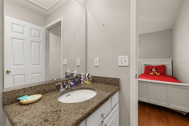 bathroom with vanity, a textured wall, and wood finished floors