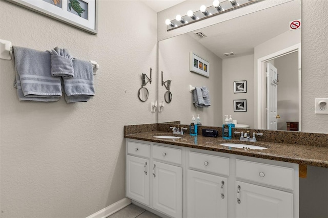 bathroom with double vanity, visible vents, and a sink