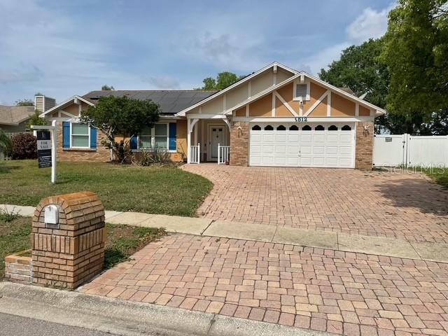 view of front facade featuring fence, decorative driveway, a garage, a front yard, and roof mounted solar panels
