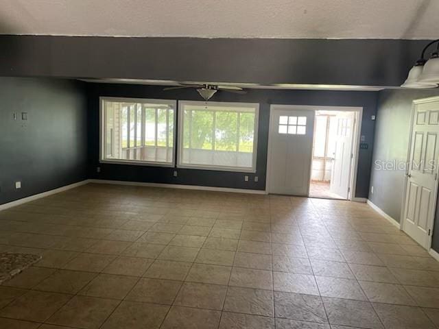 empty room with ceiling fan, baseboards, and tile patterned floors
