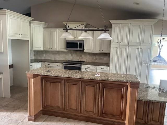 kitchen with lofted ceiling, a center island, hanging light fixtures, decorative backsplash, and appliances with stainless steel finishes