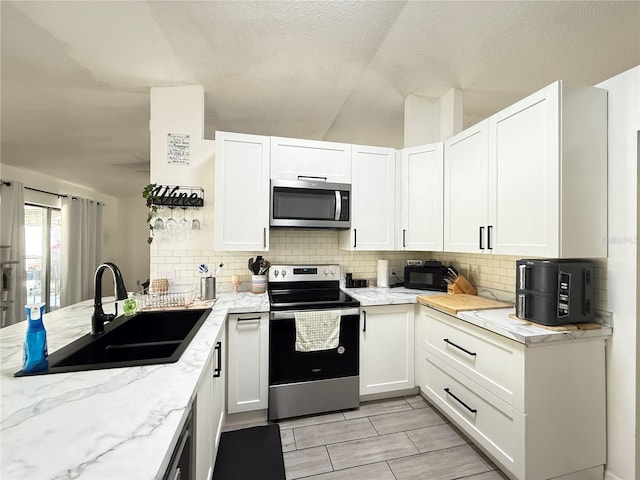 6922 Doehring Dr, Lakeland, FL 33810 - kitchen featuring light stone counters, a sink, white cabinets, and stainless steel appliances