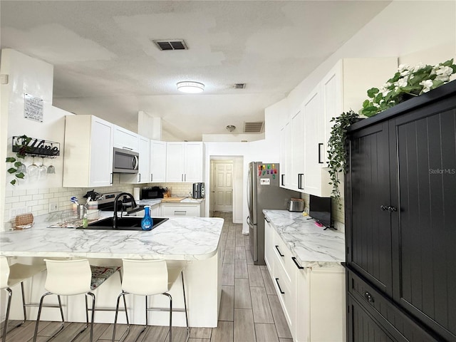 6922 Doehring Dr, Lakeland, FL 33810 - kitchen featuring a sink, a breakfast bar area, a peninsula, stainless steel microwave, and white cabinetry