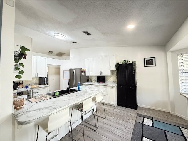 6922 Doehring Dr, Lakeland, FL 33810 - kitchen with a breakfast bar area, freestanding refrigerator, backsplash, and a peninsula