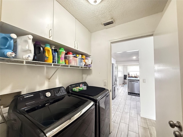 6922 Doehring Dr, Lakeland, FL 33810 - laundry room featuring visible vents, wood finish floors, a textured ceiling, washing machine and clothes dryer, and cabinet space