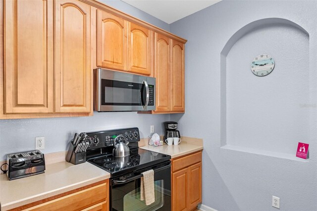 4862 Cayview Ave Unit 407, Orlando, FL 32819 - kitchen with stainless steel microwave, arched walkways, black range with electric cooktop, and light countertops