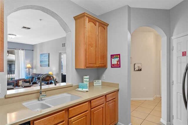 4862 Cayview Ave Unit 407, Orlando, FL 32819 - kitchen featuring visible vents, light tile patterned floors, arched walkways, a sink, and light countertops