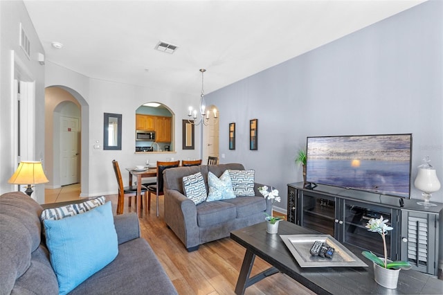 4862 Cayview Ave Unit 407, Orlando, FL 32819 - living area featuring light wood-style floors, an inviting chandelier, arched walkways, visible vents, and baseboards