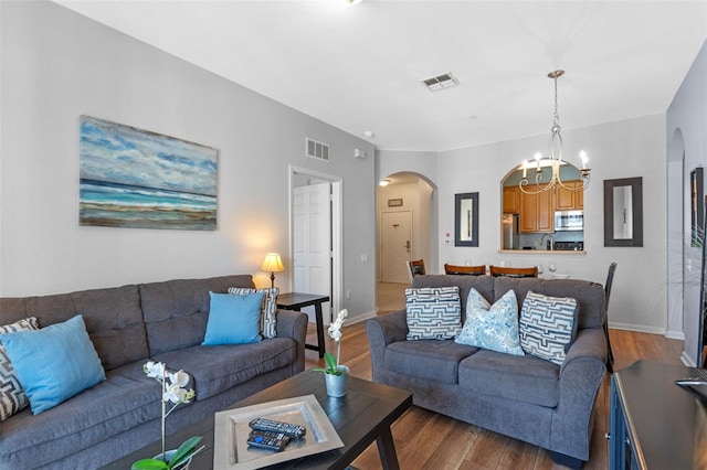 4862 Cayview Ave Unit 407, Orlando, FL 32819 - living room with baseboards, an inviting chandelier, visible vents, arched walkways, and wood finished floors