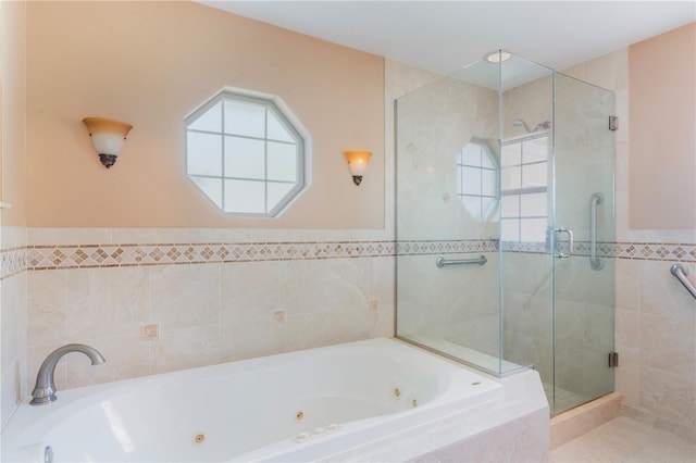 bathroom featuring wainscoting, tile walls, a stall shower, and a tub with jets