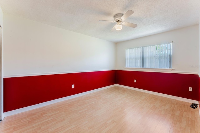 spare room featuring a textured ceiling, wood finished floors, baseboards, and a ceiling fan