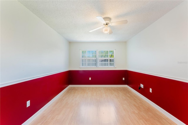 spare room with ceiling fan, a textured ceiling, baseboards, and wood finished floors