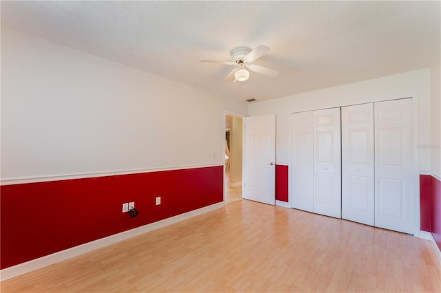 unfurnished bedroom featuring ceiling fan, a closet, baseboards, and wood finished floors
