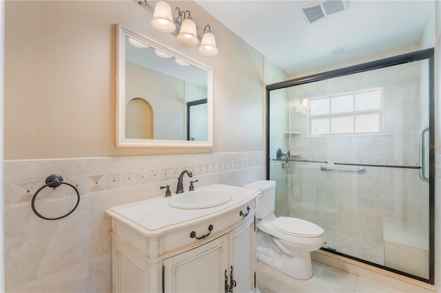 bathroom with visible vents, toilet, tile walls, a shower stall, and vanity