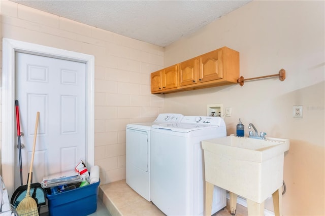 laundry area featuring independent washer and dryer, a textured ceiling, a sink, and cabinet space