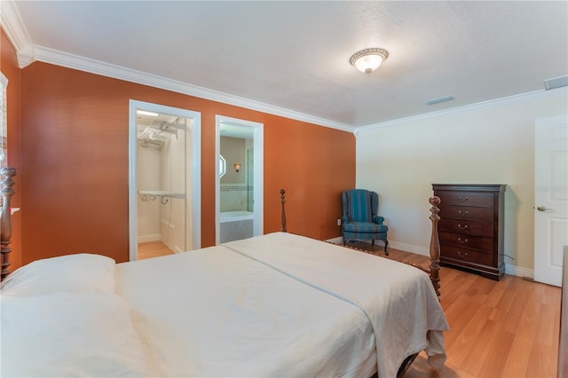 bedroom featuring visible vents, baseboards, ornamental molding, light wood finished floors, and connected bathroom
