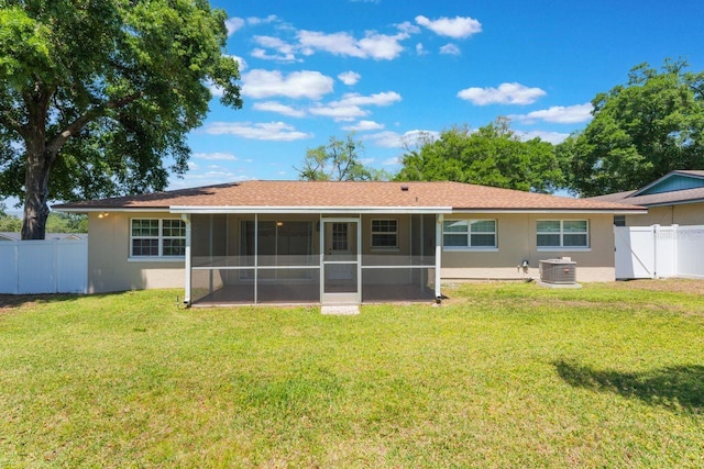 rear view of house featuring a sunroom, a yard, stucco siding, and fence