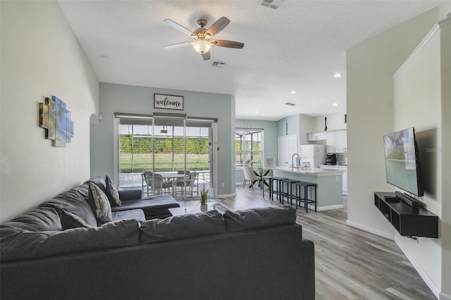 2237 Wyndham Palms Way, Kissimmee, FL 34747 - living room featuring ceiling fan, a textured ceiling, light wood-style floors, and baseboards