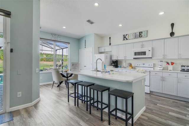 2237 Wyndham Palms Way, Kissimmee, FL 34747 - kitchen with a sink, visible vents, light wood finished floors, and white appliances