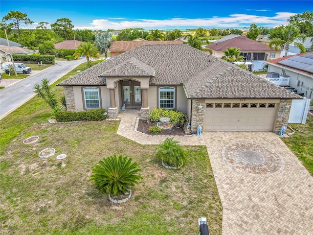 106 Meridian St, Davenport, FL 33837 - view of front facade featuring stucco siding, an attached garage, driveway, french doors, and stone siding