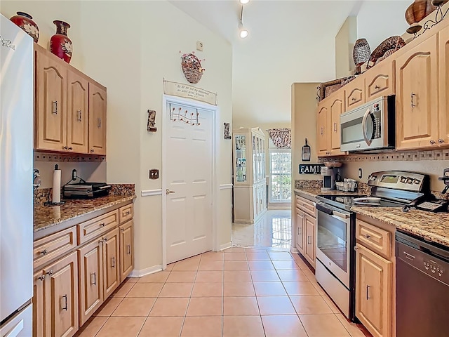 106 Meridian St, Davenport, FL 33837 - kitchen with light brown cabinetry, a towering ceiling, stainless steel appliances, and light tile patterned floors