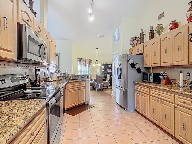 106 Meridian St, Davenport, FL 33837 - kitchen with stainless steel appliances, a peninsula, light tile patterned flooring, light brown cabinets, and high vaulted ceiling