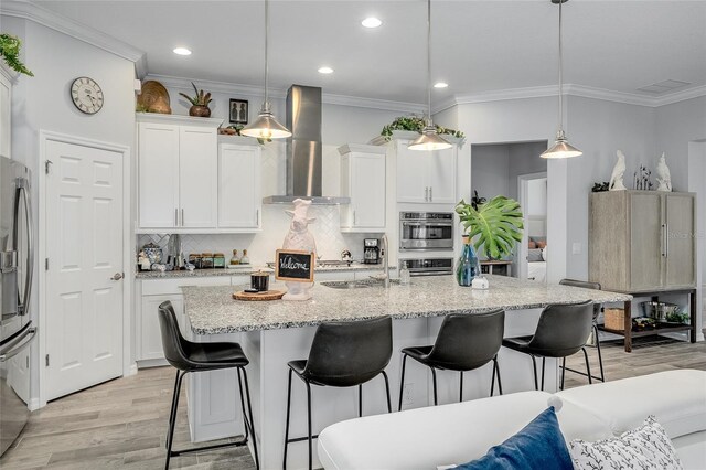 7957 Hanson Bay Pl, Kissimmee, FL 34747 - kitchen featuring a breakfast bar area, stainless steel appliances, backsplash, light wood finished floors, and wall chimney exhaust hood