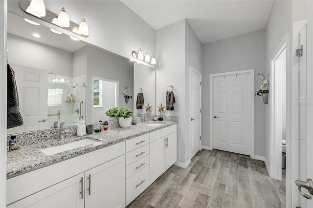 7957 Hanson Bay Pl, Kissimmee, FL 34747 - bathroom with a sink, double vanity, a stall shower, baseboards, and wood finished floors