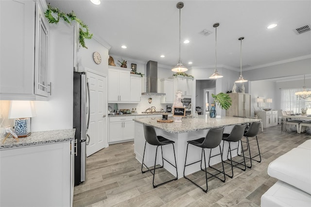 7957 Hanson Bay Pl, Kissimmee, FL 34747 - kitchen with light wood-style flooring, visible vents, ornamental molding, and wall chimney exhaust hood