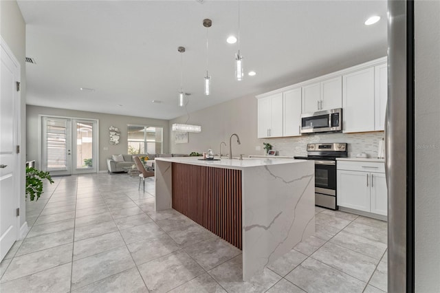 11162 Hanlon Terrace Aly, Winter Garden, FL 34787 - kitchen featuring light tile patterned floors, open floor plan, a kitchen island with sink, stainless steel appliances, and decorative backsplash