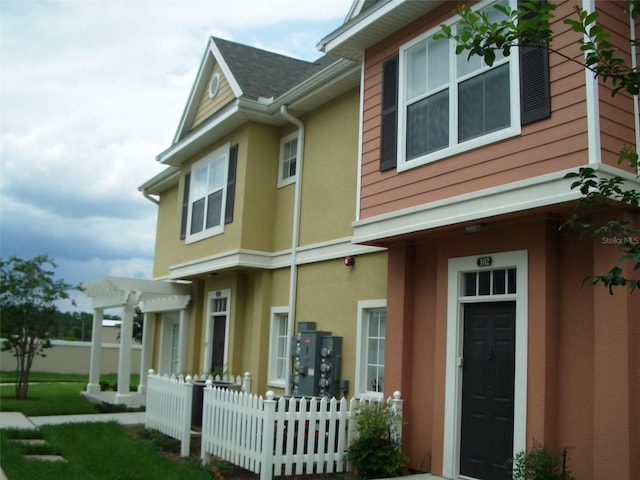 rear view of property with stucco siding and fence