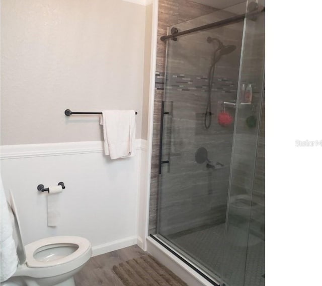 full bath with a shower stall, wood finished floors, and toilet